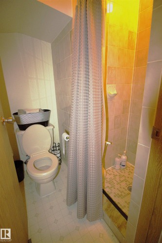 The bathroom features a shower with tiled walls and a patterned floor, and a toilet - 9347 175 Avenue, Edmonton, AB - Indoor Photo Showing Bathroom