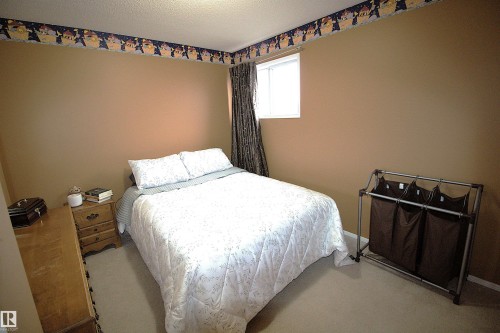 The property features neutral-toned walls, a window with dark patterned curtains, and light-colored carpeting - 9347 175 Avenue, Edmonton, AB - Indoor Photo Showing Bedroom