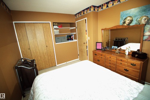 This room features warm-toned walls, a built-in shelving unit, and a door with a light wood finish - 9347 175 Avenue, Edmonton, AB - Indoor Photo Showing Bedroom