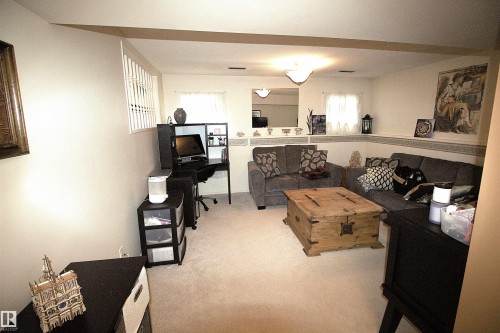 The property features a spacious room with light-colored carpeting, a window providing natural light, and a built-in shelf - 9347 175 Avenue, Edmonton, AB - Indoor Photo Showing Living Room