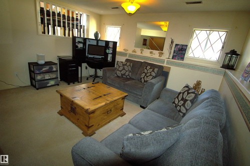 This living space features light-colored carpeting, white walls, and decorative upper windows with a unique grid pattern - 9347 175 Avenue, Edmonton, AB - Indoor Photo Showing Living Room