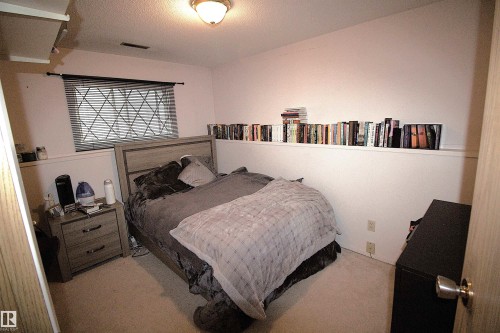 The property features a room with light-colored carpeting, a window with horizontal blinds, and a light fixture on the ceiling - 9347 175 Avenue, Edmonton, AB - Indoor Photo Showing Bedroom