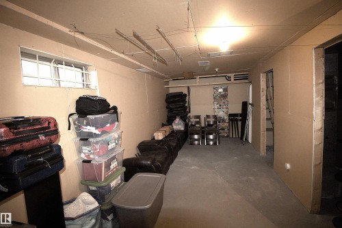 The property features a utility room with a concrete floor, a window with security bars, and exposed overhead wiring - 9347 175 Avenue, Edmonton, AB - Indoor