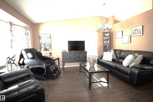 The living area features wood-look flooring, a chandelier, and a bay window - 9347 175 Avenue, Edmonton, AB - Indoor Photo Showing Living Room