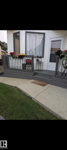 The property features a front porch with dark grey railings and steps, leading to a white entry door - 9347 175 Avenue, Edmonton, AB - Outdoor With Deck Patio Veranda