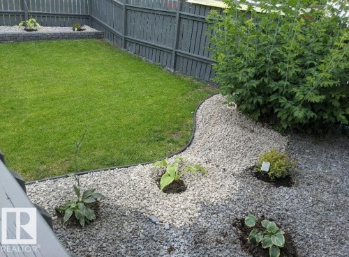 The property features a well-maintained lawn area, bordered by a gravel landscaping bed with various plantings - 9347 175 Avenue, Edmonton, AB - Outdoor