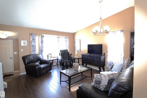 Living area featuring a spacious bay window, hardwood flooring, and a vaulted ceiling with a contemporary chandelier - 9347 175 Avenue, Edmonton, AB - Indoor Photo Showing Living Room