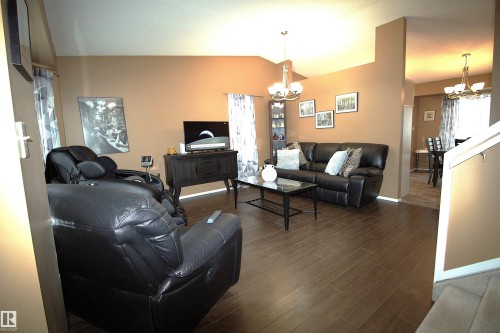 Spacious living area featuring vaulted ceilings, dark wood-look tile flooring, and a chandelier light fixture - 9347 175 Avenue, Edmonton, AB - Indoor Photo Showing Living Room