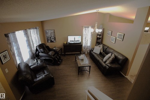 Inviting living space featuring vaulted ceilings, a ceiling light fixture, wood flooring, and windows with curtains - 9347 175 Avenue, Edmonton, AB - Indoor Photo Showing Living Room