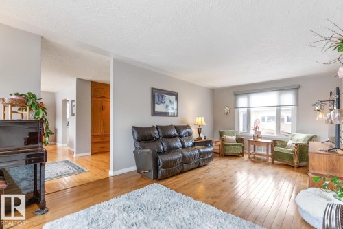 The living area features hardwood floors and a large window providing natural light - 10504 60 Street, Edmonton, AB - Indoor Photo Showing Living Room