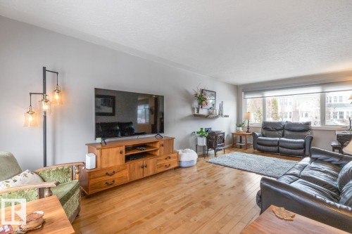 Spacious living area featuring hardwood flooring, large windows with blinds, and light gray walls - 10504 60 Street, Edmonton, AB - Indoor Photo Showing Living Room