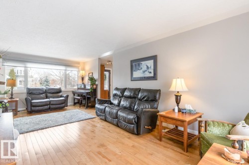 The living room features hardwood flooring, light grey walls, and a large window providing ample natural light - 10504 60 Street, Edmonton, AB - Indoor Photo Showing Living Room