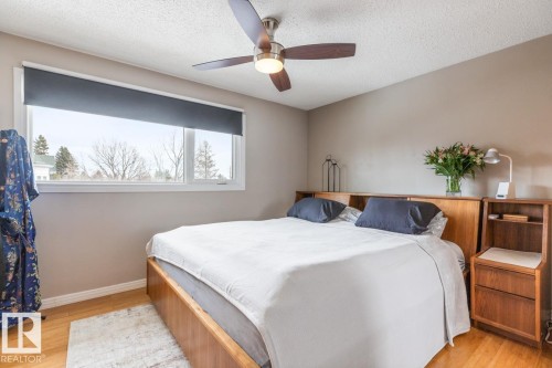 The room features a ceiling fan, a large window, and hardwood floors - 10504 60 Street, Edmonton, AB - Indoor Photo Showing Bedroom