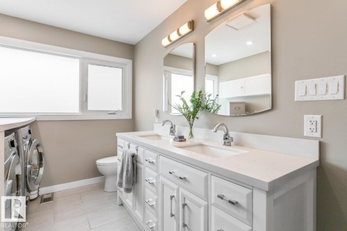 This property features a bathroom with a double vanity, a window, and a toilet - 10504 60 Street, Edmonton, AB - Indoor Photo Showing Bathroom