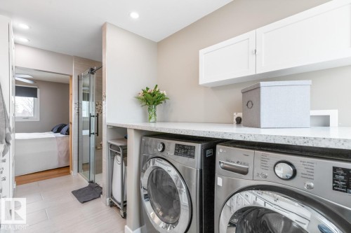 The property features a laundry area with stainless steel appliances, white cabinetry, and a spacious countertop - 10504 60 Street, Edmonton, AB - Indoor Photo Showing Laundry Room