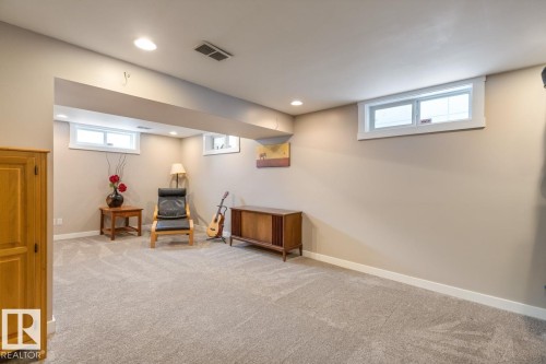 The property features a spacious room with light-colored carpeting, recessed lighting, and several windows providing natural light - 10504 60 Street, Edmonton, AB - Indoor Photo Showing Basement