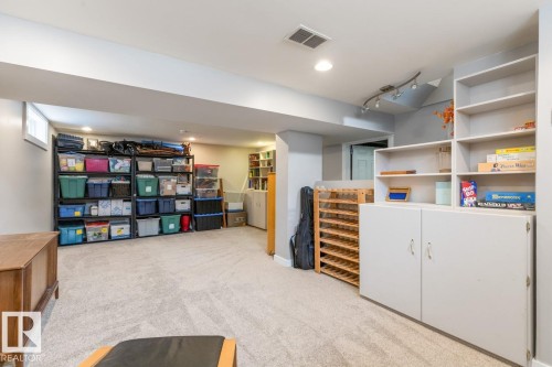 The property features a finished basement with light-colored carpeting, built-in shelving, and recessed lighting - 10504 60 Street, Edmonton, AB - Indoor