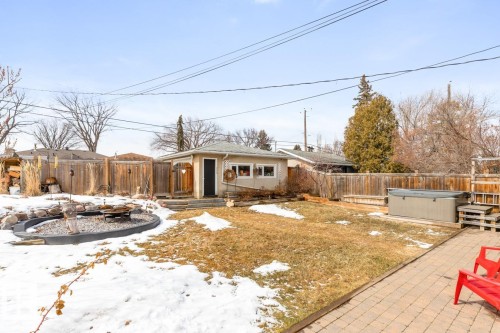 The property features an extensive yard with a lawn, a paved patio area, a hot tub, and a dedicated fire pit area - 10504 60 Street, Edmonton, AB - Outdoor