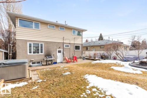 The property features a backyard with a lawn, a paved patio area, and a hot tub - 10504 60 Street, Edmonton, AB - Outdoor With Exterior