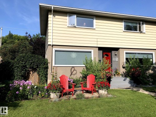 The property features a well-maintained lawn and a garden area with blooming flowers and mature greenery - 10504 60 Street, Edmonton, AB - Outdoor