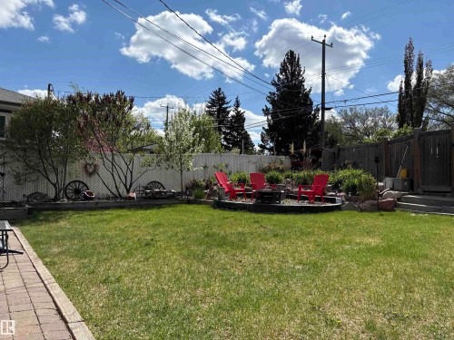 The property features an extensive backyard with a well-maintained lawn, mature trees, and a decorative white fence - 10504 60 Street, Edmonton, AB - Outdoor