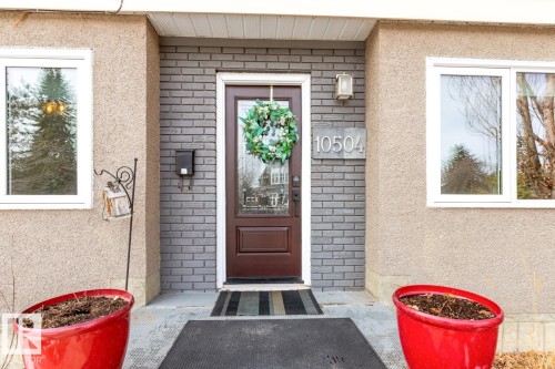 The property features an inviting front entrance with a dark wood door, flanked by brickwork and stucco siding - 10504 60 Street, Edmonton, AB - Outdoor With Exterior