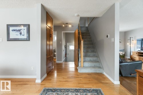 The property features hardwood floors, a carpeted staircase, and a built-in wooden cabinet - 10504 60 Street, Edmonton, AB - Indoor Photo Showing Other Room