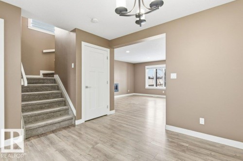 This interior space features light wood-look flooring, a carpeted staircase with white trim, and neutral-toned walls - 2 Wingate Way, Fort Saskatchewan, AB - Indoor Photo Showing Other Room