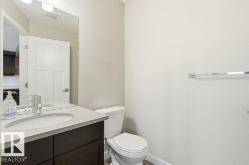 Bathroom featuring a dark wood vanity with a white countertop and an undermount sink, a toilet, and a wall-mounted mirror - 2 Wingate Way, Fort Saskatchewan, AB - Indoor Photo Showing Bathroom