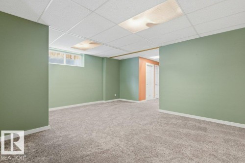 Spacious room featuring light green walls, a drop ceiling with integrated lighting, and plush grey carpeting - 2 Wingate Way, Fort Saskatchewan, AB - Indoor