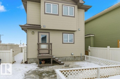 The property features light beige siding, white trim around the windows, and a white lattice fence - 2 Wingate Way, Fort Saskatchewan, AB - Outdoor With Exterior