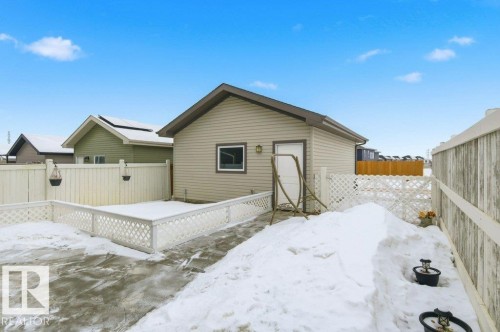 The property features a detached garage with siding and a window, a fenced yard with a gate, and a paved area - 2 Wingate Way, Fort Saskatchewan, AB - Outdoor With Exterior