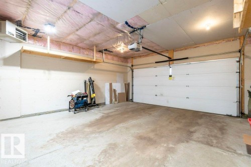 Spacious garage featuring a concrete floor, a white garage door, and exposed ceiling insulation - 2 Wingate Way, Fort Saskatchewan, AB - Indoor Photo Showing Garage