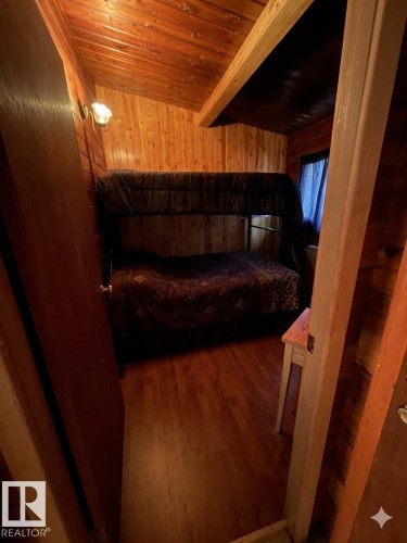 Room featuring wood-finish flooring, natural wood paneling, and a sloped ceiling with exposed wood beams - 1040 &1040 A&B Mitchell Beach Beach, Rural Leduc County, AB 