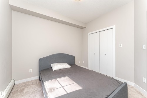 This room features light-colored walls, carpeted flooring, and a white bi-fold closet - 313 10418 81 Avenue, Edmonton, AB - Indoor Photo Showing Bedroom