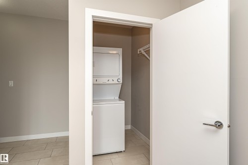 Laundry closet featuring a stackable washer and dryer, and a hanging rack - 313 10418 81 Avenue, Edmonton, AB - Indoor Photo Showing Laundry Room
