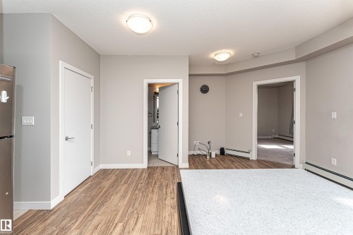 Living area featuring wood-look flooring and light-colored walls - 313 10418 81 Avenue, Edmonton, AB - Indoor Photo Showing Other Room
