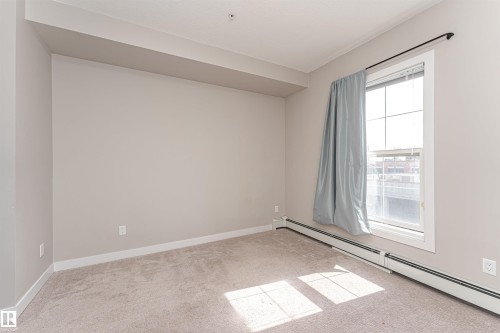 The interior room features light-colored walls, a window with a light-colored curtain, and carpeting - 313 10418 81 Avenue, Edmonton, AB - Indoor Photo Showing Other Room