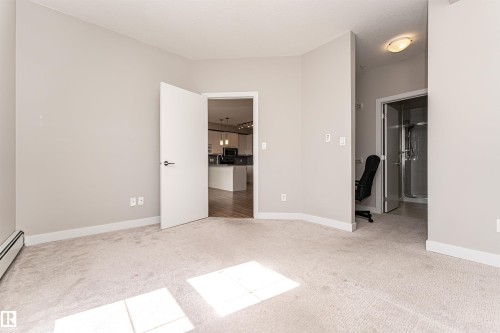 Carpeted room featuring light-colored walls and white trim - 313 10418 81 Avenue, Edmonton, AB - Indoor Photo Showing Other Room