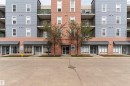 The property features a brick and siding exterior, with ground-level commercial spaces and residential units above - 313 10418 81 Avenue, Edmonton, AB  - Outdoor With Balcony With Facade 