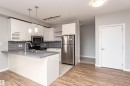 The kitchen features white cabinetry, stainless steel appliances, a grey tiled backsplash, a kitchen island with a sink, and pendant lighting - 313 10418 81 Avenue, Edmonton, AB  - Indoor Photo Showing Kitchen 