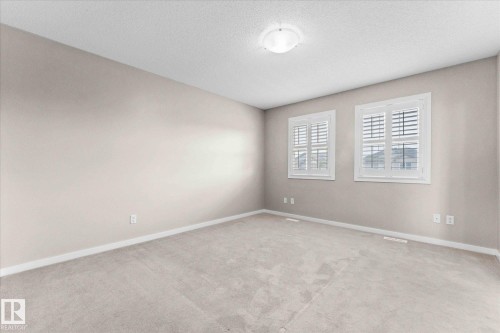 The room features neutral-toned walls and carpeting, two windows with white plantation shutters, and a ceiling-mounted light fixture - 84 Calvert Wynd, Fort Saskatchewan, AB - Indoor Photo Showing Other Room