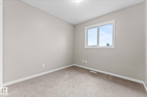 This room features light-colored carpet, neutral painted walls, and a window providing natural light - 84 Calvert Wynd, Fort Saskatchewan, AB - Indoor Photo Showing Other Room