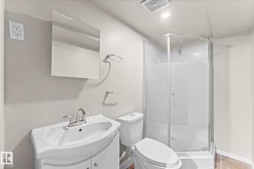 Bathroom featuring a white vanity with a sink and faucet, a wall-mounted mirror, a toilet, and a glass-enclosed shower with a white base - 84 Calvert Wynd, Fort Saskatchewan, AB - Indoor Photo Showing Bathroom