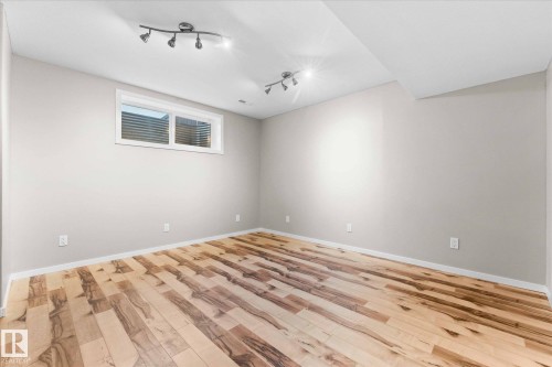 This room features striking wood flooring, light-toned walls, and a window providing natural light - 84 Calvert Wynd, Fort Saskatchewan, AB - Indoor Photo Showing Other Room