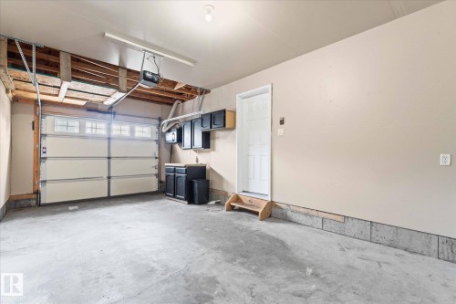 The garage features a concrete floor, a white garage door with windows, and dark cabinetry with a countertop - 84 Calvert Wynd, Fort Saskatchewan, AB - Indoor Photo Showing Garage