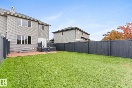 The property features a spacious backyard with a well-maintained lawn and a dark-stained wooden fence - 84 Calvert Wynd, Fort Saskatchewan, AB - Outdoor