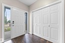 Entryway featuring a white paneled door with sidelight windows, dark tile flooring, and white bifold closet doors - 84 Calvert Wynd, Fort Saskatchewan, AB  - Indoor Photo Showing Other Room 