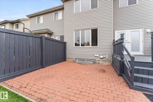 The property features a private patio with red interlocking pavers, a privacy fence, and steps leading to a deck and French doors - 84 Calvert Wynd, Fort Saskatchewan, AB - Outdoor With Exterior