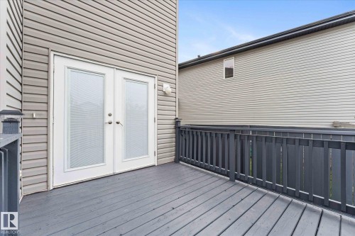 The property features a private deck with gray wood flooring and a matching railing - 84 Calvert Wynd, Fort Saskatchewan, AB - Outdoor With Deck Patio Veranda With Exterior